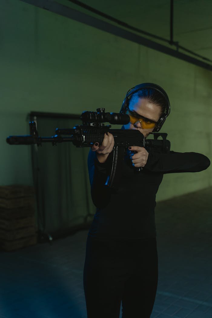 Focused woman aiming a sniper rifle indoors at a shooting range.
